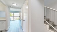 Located at 5662 La Mirada Ave in the heart of Los Angeles, this two-story, 2-bedroom, 3-bathroom home offers a clean, modern aesthetic across two well-proportioned floors. Light-toned luxury vinyl plank flooring runs throughout, complementing the neutral gray and white color palette that lends a bright, contemporary feel to every room.

The main level features an open-concept living and kitchen area. The living room is a standout space, highlighted by a sleek fireplace and expansive sliding glass doors that open onto a private balcony with lush tree-lined views, flooding the room with natural light. The kitchen is designed for functionality, featuring white cabinetry, stainless steel appliances including a refrigerator, range, and microwave, a light stone countertop, and a pass-through bar that connects seamlessly to the living area.

Upstairs, the two bedrooms are generously sized and filled with natural light from well-placed windows with views of surrounding greenery. The primary bedroom includes a closet and ample space for furnishings. Each of the three bathrooms is clean and practical, with one featuring a full shower/tub combination with chrome fixtures. A hallway with built-in storage and recessed lighting ties the layout together efficiently, making this a well-designed and move-in ready Los Angeles home.