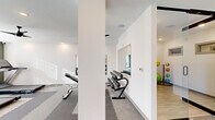 Located at 10 Calm Water Dr in Asheville, NC, this fitness center offers a thoughtfully designed exercise facility spread across a single floor. The space is defined by a clean, modern aesthetic, featuring bright white walls accented by sage green focal walls, recessed lighting, and multiple ceiling fans that ensure comfortable airflow throughout workouts.

The main exercise room is divided into functional zones. The cardio area is equipped with multiple treadmills, an elliptical trainer, and stationary bikes, positioned alongside large windows fitted with blinds that allow ample natural light while offering privacy. A wall-mounted flat-screen television accompanies this section for entertainment during cardio sessions.

A dedicated free weights area features a full dumbbell rack with a large wall mirror, providing users with proper form visibility. Adjacent to this, a stability and functional training zone houses medicine balls, stability balls, and a multi-use cable machine. The flooring throughout consists of interlocking foam and rubber tiles, offering cushioning and safety across all training zones.

The hallway entry, accessible via a full-length glass sliding door, provides a clean transition into the facility. Decorative touches, including framed artwork and small potted plants, contribute to an inviting atmosphere. The space is well-lit, well-ventilated, and comprehensively equipped to support a wide range of fitness activities.