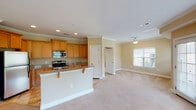 Located at 1505 New Garden Rd in Greensboro, NC, this single-floor residence offers a thoughtfully designed open-concept layout that seamlessly connects the kitchen and living areas. The kitchen is well-equipped with warm honey-toned cabinetry, granite countertops, stainless steel appliances including a refrigerator, electric range, and built-in microwave, and tile flooring. A breakfast bar with seating extends from the kitchen island, creating a natural transition into the open living space. Crown molding adds a refined architectural detail throughout the main living areas, which feature soft neutral-toned carpet and recessed lighting. The spacious living room is bathed in natural light from multiple windows and glass French doors that open to an outdoor area, complemented by a ceiling fan overhead. Bedrooms are generously sized with plush carpeting, ceiling fans, and ample natural light. The bathrooms are finished with granite-topped vanities, warm wood cabinetry, and tile flooring. The primary bathroom includes access to a walk-in closet with built-in shelving. Throughout the home, a warm, neutral color palette creates a bright and welcoming ambiance.