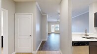 Located at 5215 Millenia Boulevard in Orlando, Florida, this one-bedroom, one-bathroom residence offers a well-designed single-floor layout with thoughtful finishes throughout. The open-concept living, dining, and kitchen area serves as the heart of the home, featuring warm hardwood-style flooring, crown molding, and a ceiling fan that add character to the space. A sliding door with flanking windows invites abundant natural light and leads to a private balcony overlooking the landscaped community grounds. The kitchen is outfitted with dark espresso cabinetry, a herringbone tile backsplash, stainless steel appliances including a refrigerator, range, and microwave, and a curved white breakfast bar that provides additional prep and seating space. Tile flooring in the kitchen and entryway transitions seamlessly to hardwood-style flooring throughout the main living areas. The bedroom is generously proportioned, offering a ceiling fan, a large window with natural light, and access to multiple closets for ample storage. The full bathroom features dark vanity cabinetry with a white countertop, a large mirror, tile flooring, and a tub-shower combination. A dedicated laundry area adds everyday convenience. Neutral gray walls and clean white trim create a cohesive, move-in-ready aesthetic throughout.