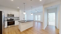 Located at 510 Cedar Tree Rd in Wellford, SC, this single-story 2-bedroom, 2-bathroom home offers a clean, modern aesthetic throughout. The open-concept kitchen and living area serves as the heart of the home, anchored by a central island with a dark granite countertop, undermount sink, and stylish globe pendant lighting. White shaker-style cabinetry, a hexagonal tile backsplash, and stainless steel appliances — including a French door refrigerator, range, and microwave — complete the well-equipped kitchen. Light hardwood-style flooring extends through the main living areas, enhancing the bright, airy atmosphere. The living space flows toward French doors that invite natural light from outside. Both bedrooms feature soft carpeting and ceiling fans, with the primary bedroom offering a generous walk-in closet with wire shelving. The bathrooms are finished with white vanity cabinetry, dark countertops, and hardwood-style flooring. A dedicated laundry room houses a full-size washer and dryer with overhead wire shelving for added storage. Two closets and a hallway round out the thoughtful, functional layout of this well-designed home.