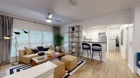 This thoughtfully designed single-floor residence in Jacksonville, Florida, offers a cohesive blend of modern aesthetics and functional living. Light wood-look flooring flows throughout the main living areas, complemented by crown molding and crisp white walls that create a bright, welcoming atmosphere.

The open-concept living room is generously proportioned, featuring a ceiling fan, large windows with ample natural light, and direct sightlines to the kitchen. A freestanding open shelving unit acts as a stylish room divider, while the space comfortably accommodates both a lounge and media area.

The kitchen is outfitted with white shaker cabinetry, dark granite countertops, subway tile backsplash, and a full suite of stainless steel appliances including a refrigerator, range, microwave, and dishwasher. A breakfast bar with seating bridges the kitchen to the living area.

A dedicated dining nook features a striking floral watercolor accent wall, a round white table, and wicker seating, offering an intimate setting for meals.

The bedroom showcases a bold black-and-white abstract accent wall, plush carpeting, a ceiling fan, and large windows. The full bathroom includes a wide vanity with dark granite counters, white cabinetry, and a shower-tub combination. An in-unit laundry area with washer and dryer adds everyday convenience.
