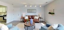This single-floor unit offers a thoughtfully designed layout with a cohesive, neutral color palette throughout. The living room serves as the heart of the space, featuring light gray walls, wood-look laminate flooring, a textured ceiling, and track lighting that enhances the room's warm ambiance. Large windows allow natural light to pour in, creating a bright and welcoming atmosphere.

The kitchen is well-equipped with white shaker-style cabinetry, granite-look countertops, and a full suite of stainless steel appliances including a refrigerator, gas range, and dishwasher. The wood-look flooring continues seamlessly into the adjacent dining area, which is accented by a stylish pendant light fixture and offers a comfortable, open setting for meals.

The bedrooms are generously sized with wide windows that frame outdoor views, wood-look laminate flooring, textured ceilings, and sliding or standard closets providing ample storage. The bathroom features classic hexagonal tile flooring, soft gray walls, and a clean, minimal aesthetic that complements the overall design of the unit.

Throughout, the space maintains a consistent, modern-casual style with clean lines, light tones, and practical finishes that make it both functional and visually appealing.