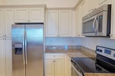 Located at 4471 Western Gails Ct in Fort Myers, Florida, this single-story residence offers three bedrooms, two bathrooms, and a well-distributed layout across a generously sized floor plan. The interior is characterized by soaring vaulted ceilings that amplify the sense of openness throughout the main living areas, complemented by rich wood-look flooring that extends through the hallways and living spaces.

The hallways feature elegant arched doorways that connect the living room, kitchen, and bedroom wings, lending architectural character to the home. The kitchen is appointed with granite countertops, raised white cabinetry extending to the ceiling, a stainless steel refrigerator, and tile flooring, providing both style and practicality. A dedicated laundry room houses a full-size washer and dryer.

The spacious primary bedroom includes a walk-in closet with wire shelving, and its en-suite bathroom offers a soaking tub, a separate glass-enclosed shower, tile flooring, and granite vanity countertops. Secondary bedrooms feature neutral carpet and window blinds that allow natural light. The living area provides direct access to a balcony with views of surrounding greenery, enhancing the Florida living experience.
