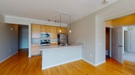 Located at 415-425 N Front St in Columbus, Ohio, this single-floor unit offers a well-designed layout that balances functional living spaces with comfortable finishes throughout. The open-concept kitchen and living area serves as the heart of the unit, featuring warm hardwood flooring, crown molding, and a peninsula with an integrated sink that separates the kitchen from the living space. The kitchen is equipped with stainless steel appliances, including a refrigerator, electric range, and microwave, complemented by light wood cabinetry and track lighting overhead. Pendant lights above the peninsula add a modern touch, while natural light filters in through nearby windows.

The living area is generously proportioned, with hardwood floors continuing seamlessly from the kitchen. The bedrooms are carpeted for comfort, each benefiting from large windows that bring in abundant natural light and views of the surrounding urban streetscape. The unit includes two bathrooms — one featuring a soaking tub with shower surround and white vanity, the other a half-bath style with matching white cabinetry. A dedicated in-unit laundry area with a full-size washer and dryer rounds out the practical amenities of this well-appointed space.