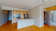 Located at 415-425 N Front St in Columbus, Ohio, this single-floor unit offers a well-designed layout that balances functional living spaces with comfortable finishes throughout. The open-concept kitchen and living area serves as the heart of the unit, featuring warm hardwood flooring, crown molding, and a peninsula with an integrated sink that separates the kitchen from the living space. The kitchen is equipped with stainless steel appliances, including a refrigerator, electric range, and microwave, complemented by light wood cabinetry and track lighting overhead. Pendant lights above the peninsula add a modern touch, while natural light filters in through nearby windows.

The living area is generously proportioned, with hardwood floors continuing seamlessly from the kitchen. The bedrooms are carpeted for comfort, each benefiting from large windows that bring in abundant natural light and views of the surrounding urban streetscape. The unit includes two bathrooms — one featuring a soaking tub with shower surround and white vanity, the other a half-bath style with matching white cabinetry. A dedicated in-unit laundry area with a full-size washer and dryer rounds out the practical amenities of this well-appointed space.