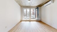 This contemporary 51 square meter apartment in Montreal's Saint-Patrick district offers a harmonious blend of modern design and industrial charm. The open-concept layout seamlessly integrates the living room and kitchen, creating a spacious feel within the compact floor plan. The living area is bathed in natural light from large windows, which also provide urban views and access to a balcony.

The kitchen is a standout feature, boasting sleek gray cabinetry, a generous island with a white countertop, and stainless steel appliances. It's equipped with ample storage and workspace, perfect for culinary enthusiasts.

The bedroom, measuring 19 square meters, is generously sized and features the same industrial-style concrete ceiling found throughout the apartment. This unique architectural element adds character and height to the space.

The bathroom is modern and functional, with a large-format tile floor, a stylish vanity, and a combination tub-shower. Throughout the apartment, warm wood-toned flooring contrasts beautifully with the white walls and concrete ceilings, creating a cozy yet contemporary ambiance.

Despite its efficient size, the apartment's thoughtful design ensures no space is wasted, offering a comfortable and stylish urban living experience in the heart of Montreal.