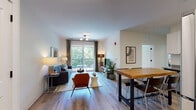 Located at 87 Union St in New Haven, CT, this well-appointed single-floor residence offers a thoughtfully designed open-concept layout with modern finishes throughout. Light-toned hardwood-style flooring flows seamlessly across the living, dining, and kitchen areas, creating a cohesive and airy atmosphere. The living room is bright and welcoming, anchored by large sliding glass doors that open to a private balcony overlooking a canopy of mature trees, filling the space with abundant natural light. Adjacent to the living area, the kitchen is outfitted with crisp white cabinetry, stainless steel appliances, and stone-toned countertops, complemented by a substantial wood-top island that doubles as a dining and gathering space. Two generously sized bedrooms each feature large windows with verdant outdoor views, providing a calm and restful environment. The bathrooms are finished with clean, contemporary fixtures, including matte black hardware, a soaking tub with tiled surround, and white vanities with stone countertops. A dedicated in-unit laundry closet with full-size washer and dryer adds everyday convenience. Throughout the residence, a neutral color palette and clean architectural lines create a modern, comfortable living environment.