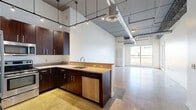 Located at 1500 N Sixth St in Harrisburg, PA, this modern urban loft offers a thoughtfully designed one-bedroom, one-bathroom layout with a distinctive industrial-chic aesthetic. Polished concrete floors flow seamlessly throughout the entire space, complementing the exposed ductwork and soaring ceilings that define the open-concept living area. Large windows flood the living space with natural light and provide views of the surrounding cityscape.

The kitchen is a standout feature, equipped with rich dark-wood cabinetry, stainless steel appliances including a refrigerator, range, microwave, and dishwasher, and granite-style countertops. A peninsula with a built-in sink adds both functionality and style, while track lighting overhead highlights the space's contemporary character.

The spacious primary bedroom benefits from its own window and continues the polished concrete flooring, creating a cohesive, modern feel. An adjacent walk-in closet offers an organized shelving and hanging system with rich wood finishes, providing ample storage capacity.

The bathroom features a clean, minimalist design with a tub/shower combination, light wood vanity with dark countertop, and recessed lighting. A hallway connects the rooms efficiently, rounding out this well-planned urban residence.