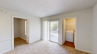 Located at 2 Wyndham Dr in Hampton, Virginia, this single-floor, one-bedroom, one-bathroom unit offers a practical and well-organized layout. The open living and kitchen area greets you upon entry, where warm hardwood-style flooring contrasts with plush carpeting in the living space. The kitchen is efficiently designed with warm wood cabinetry, dark granite-style countertops, a double stainless steel sink, and a full suite of stainless steel appliances including a gas range, microwave, dishwasher, and refrigerator. Pendant lighting overhead adds a clean, finished look to the space. A half-wall peninsula separates the kitchen from the living area, enhancing the open feel while maintaining defined zones. The bedroom features soft carpeting, a ceiling fan with light fixture, a natural light-filled window with blinds, and access to a dedicated closet. The bathroom is bright and clean, finished in white tile with a full bathtub and shower combination, chrome fixtures, and classic white fixtures throughout. The overall aesthetic is clean and neutral, offering a comfortable and functional living environment in a convenient Hampton location.