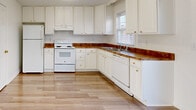 Located at 1339 Riddle Ave in Morgantown, West Virginia, this three-floor residence offers a clean, modern aesthetic defined by light hardwood flooring, crisp white walls, and an abundance of natural light throughout. The layout spans multiple levels, providing generous living space across each floor.

The kitchen is well-appointed with white cabinetry, warm-toned countertops, and white appliances including a refrigerator, electric range, and dishwasher. A window above the sink allows natural light to brighten the workspace, and the adjoining hardwood floors extend seamlessly into the surrounding areas.

The living and bedroom spaces are bright and open, with large windows dressed in sheer vertical blinds that filter sunlight across the hardwood floors. Several rooms include ceiling fans and closets, with one bedroom featuring a double-door closet. Sliding glass doors in multiple rooms open directly onto outdoor balconies with white railing, offering pleasant exterior views.

The bathrooms maintain the home's clean aesthetic, each featuring white vanities with integrated sinks, large mirrors, chrome fixtures, and tile flooring. The overall ambiance of the residence is light, airy, and well-maintained throughout all three floors.