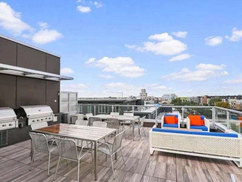 Rooftop patio with grills, dining tables, and lounge seating with city views.