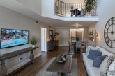 Located at 1529 La Quinta Cir in Upland, CA, this two-story home combines thoughtful design with functional living spaces throughout both levels. The main floor opens into a bright, airy living room distinguished by dramatically vaulted ceilings and generous natural light streaming through large windows fitted with blinds and sheer curtains. Wood-style flooring flows seamlessly through the living and dining areas, lending warmth and continuity. The dining area accommodates a counter-height table with ample space, while decorative wall art and pendant lighting add character.

The kitchen features rich, dark wood cabinetry, granite-style countertops, a tile backsplash, and a full suite of stainless steel appliances, including a range, dishwasher, and microwave. A full bathroom on the main level includes a tub-shower combination, single vanity, and large mirror.

Upstairs, vaulted ceilings continue into a versatile loft-style space currently used as a home office, with a wrought-iron staircase railing adding an architectural accent. The bedrooms are carpeted and well-lit, with windows offering views of surrounding greenery. The primary bedroom connects to a dressing area with mirrored closet doors, a vanity, and direct access to an ensuite, completing this well-organized home.
