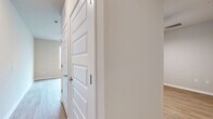 Located at 4902 Cosmos Circle in Wimauma, Florida, this efficiently designed single-floor space offers a clean, modern aesthetic with a thoughtful layout. Light wood-look flooring runs throughout, creating a cohesive and bright atmosphere across every room.

The open-concept kitchen and living area serves as the heart of the unit. The kitchen is well-appointed with white cabinetry, a full suite of stainless steel appliances including a refrigerator with ice maker, electric range, and over-the-range microwave, plus a peninsula counter that provides additional workspace and a natural division between the kitchen and living area. Large windows along one wall flood the space with abundant natural light, enhancing the airy, open feel of the room. Recessed lighting and a ceiling fan add functionality and comfort overhead.

The bedroom area features warm neutral-toned walls and a high clerestory window that brings in additional natural light while maintaining privacy. A dedicated closet with panel-style double doors provides organized storage.

The full bathroom is clean and modern, featuring a walk-in glass-door shower, a white vanity with ample cabinet storage, a framed mirror, and consistent wood-look flooring. The neutral palette and simple finishes throughout the space lend it a fresh, move-in-ready appeal.