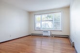 Located at 1018 Mayfair Ave in Madison, Wisconsin, this single-floor, one-bedroom, one-bathroom unit offers a practical and comfortable layout. Warm hardwood flooring flows throughout the living areas and bedroom, lending a cohesive and inviting feel to the space. The entrance leads into a hallway that connects the key areas of the home efficiently.

The living room is generously proportioned, featuring a large window dressed with vertical blinds that allow ample natural light to fill the room. A wall-mounted air conditioning unit and baseboard heating ensure year-round comfort. The kitchen is positioned adjacent to the living area and is equipped with a gas range, refrigerator, and overhead cabinetry, with tile flooring and a ceiling fan overhead.

The bedroom offers a comfortable footprint with its own ceiling fan, a window with natural light, and access to multiple closets — three in total throughout the unit — providing strong storage options. The bathroom includes a wide vanity with an extended countertop, a large mirror with Hollywood-style lighting, and durable tile flooring. Rich, dark-stained wood doors and trim add a classic contrast throughout the unit, complementing the neutral wall tones for a clean, functional aesthetic.
