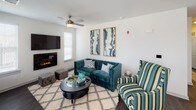 This single-floor residence offers a thoughtfully designed layout that balances comfort and functionality throughout. The open-concept kitchen is a standout feature, showcasing rich dark cabinetry, granite countertops with a dual-basin sink, a subway tile backsplash, and black appliances including a range, built-in microwave, and refrigerator. Pendant lighting and track lighting illuminate the space, while a breakfast bar provides additional seating and prep space. Dark hardwood-style flooring flows through the main living areas, adding warmth and cohesion to the design. The living room is a welcoming retreat, centered around a modern electric fireplace set beneath a wall-mounted television, complemented by a ceiling fan and natural light from large windows. The bedrooms are carpeted for comfort, each featuring ceiling fans and generous windows. One bedroom includes direct access to an outdoor area through sliding glass doors. The bathrooms are well-finished, with tile-surround soaking tubs, dark wood vanities, white countertops, and hardwood-style flooring. A walk-in closet is accessible from one of the bathrooms. Completing the home is an attached garage with an automatic opener, offering secure and convenient parking or additional storage space.