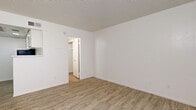 Located at 3708 W Camelback Rd in Phoenix, Arizona, this single-floor unit offers a efficiently designed layout comprising a living room and a full bathroom. Light wood-look luxury vinyl flooring runs throughout the entire space, lending warmth and visual continuity to every room. The living area is bright and open, featuring crisp white walls, a textured ceiling, and a window fitted with vertical blinds that allows natural light to filter in. A front entry door opens directly into this main living space, keeping the layout simple and accessible. A compact kitchen area is defined by a white pass-through counter and overhead cabinetry, seamlessly connecting to the living space while maximizing the use of available square footage. Ceiling vents indicate a central HVAC system for year-round comfort. The bathroom is neatly appointed with a white vanity featuring under-sink storage, a wall-mounted medicine cabinet with mirror, and a walk-in shower, all finished in a clean, neutral palette. The consistent use of white throughout the walls, trim, and fixtures creates a cohesive, well-lit environment. Overall, this unit presents a functional and tidy space suited for efficient everyday living in the heart of Phoenix.