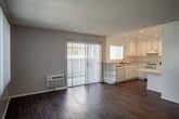 Located at 489 S Chatham Cir in Anaheim, California, this single-floor residence offers a thoughtfully laid-out interior with a clean, bright aesthetic throughout. The open-concept living and dining area is finished with warm wood-look flooring and textured ceilings, creating a welcoming atmosphere. Large sliding glass doors fitted with vertical blinds allow an abundance of natural light to pour in while providing direct access to an outdoor area. A front-facing window further brightens the space with views of the surrounding greenery.

The kitchen is efficiently designed in a U-shaped layout, featuring crisp white cabinetry with ample upper and lower storage, light-toned stone-look countertops, a double-basin sink, a gas range with overhead ventilation, and recessed lighting. A peninsula with open shelving connects the kitchen seamlessly to the living area, enhancing the open flow of the space.

The bathroom is finished with a granite-style countertop vanity, a framed mirror with medicine cabinet, and neutral tiling, maintaining the home's consistent, clean palette. Additional interior space includes a carpeted area that transitions naturally from the main living zone. The unit also features a wall-mounted HVAC unit, ensuring year-round climate comfort. Overall, the space presents a functional and well-maintained interior in a convenient Anaheim location.