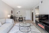 This single-floor residence in Richmond, Virginia offers a well-organized and comfortable layout. The living room is a welcoming focal point, featuring large sliding glass doors that flood the space with natural light and provide direct access to an outdoor balcony with views of the surrounding greenery. Soft carpeting and a textured ceiling add warmth to the room, which flows openly into a dedicated dining area complete with carpet flooring and wall décor accents.

The kitchen is efficiently designed with white cabinetry, dark granite-style countertops, a double-basin stainless steel sink, and stainless steel appliances including a gas range and dishwasher. Tile flooring and under-cabinet lighting enhance both function and aesthetics.

The primary bedroom is a serene retreat featuring a shiplap-style accent wall, plush carpet, a broad window dressed with rich blue curtains, and ample natural light. A second bedroom offers versatility with its own shiplap accent wall, striped area rug, and a loft-style bed frame that creates space for a built-in desk workspace below—ideal for study or remote work.

The bathroom is clean and bright, featuring tile flooring, a tub-shower combination, and a vanity with dark countertops. Throughout the residence, a neutral color palette and consistent finishes create a cohesive and inviting atmosphere.