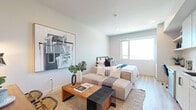 Located in the vibrant North Park neighborhood of San Diego, this modern single-floor studio offers a thoughtfully designed open-concept layout that seamlessly integrates living, sleeping, and dining areas. Light wood flooring runs throughout, lending warmth and continuity to the entire space.

The kitchen is sleek and well-appointed, featuring light wood cabinetry with matte black hardware, a white tile backsplash, stainless steel appliances including a full-size refrigerator, dishwasher, and built-in microwave, and a functional countertop workspace. The kitchen flows directly into the main living area, making the space feel connected and practical.

The living and sleeping area is bright and airy, with a large window that frames expansive city views and fills the room with natural light. A wall-mounted mini-split HVAC system ensures year-round comfort. The space accommodates a full living arrangement with a sofa, coffee table, wall-mounted TV, and a compact dining setup, all within an efficient and stylish footprint.

Crisp white walls provide a neutral backdrop that enhances the sense of openness, while recessed lighting and modern wall sconces add layered illumination. The overall aesthetic is contemporary and clean, reflecting a well-planned urban living environment ideally situated in one of San Diego's most walkable and dynamic communities.