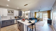 Located in Daytona Beach, FL, this well-appointed 2-bedroom, 2-bathroom residence offers a thoughtfully designed single-floor layout that blends modern style with everyday functionality. The open-concept kitchen and living area serves as the heart of the home, showcasing two-tone cabinetry in crisp white and slate gray, quartz countertops, a stainless steel dishwasher, subway tile backsplash, and a center island with bar seating illuminated by a sleek pendant light fixture. The kitchen flows effortlessly into the living room, which features a ceiling fan, large windows with natural light, and access to an outdoor area framed by golden drape panels. The primary bedroom is a comfortable retreat with a ceiling fan, wide windows, and direct access to its own en-suite bathroom. The primary bath is well-appointed with gray shaker-style cabinetry, a quartz vanity, and a glass-enclosed walk-in shower with large-format tile. The second bedroom mirrors the same clean aesthetic with natural light and a ceiling fan. A second full bathroom with a matching vanity design serves the additional bedroom. Light wood-tone flooring runs throughout, lending warmth and continuity to every room. A dedicated closet completes this refined and practical floor plan.