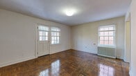 Located at 5024 Call Pl SE in Washington, DC, this two-bedroom, one-bathroom residence is designed for comfortable, efficient living on a single floor. The open living room is a welcoming centerpiece, featuring plush wall-to-wall carpeting, neutral beige walls, and an abundance of natural light streaming through large windows and a glass-paneled door that overlooks the outdoors. A pass-through counter connects the living area to the kitchen, which is equipped with warm wood cabinetry, a stainless steel sink, electric range, and a full-size refrigerator, all set over easy-care hardwood-style flooring. Both bedrooms continue the carpeted, light-toned aesthetic and are well-served by generous closet space — the primary bedroom features a dedicated closet with a hanging rod, while the second bedroom benefits from two closets, offering ample storage. Each bedroom receives natural light through its own window with views of the surrounding neighborhood. The full bathroom is clean and straightforward, with white tile flooring, a tiled tub-shower combination, and classic white fixtures. With three total closets throughout the home, storage is a practical highlight of this thoughtfully laid-out residence.