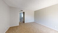 Located at 3528 E Second St in Tucson, Arizona, this single-floor 2-bedroom, 2-bathroom unit offers a practical and efficient layout designed to maximize every square foot. The living area features light wood-look flooring and is anchored by a ceiling fan, creating a comfortable gathering space that flows directly into the kitchen. The galley-style kitchen is outfitted with rich dark wood cabinetry extending to the ceiling, light countertops, a gas range, and a full-size refrigerator, providing functional storage and workspace within a compact footprint. Both bedrooms are carpeted with neutral tones and textured ceilings, offering a quiet retreat. The primary bedroom is notably spacious, featuring a window that brings in natural light. The second bedroom is equally comfortable, also with carpeting and a window. Three closets throughout the unit provide generous storage options. A connecting hallway links the bedrooms and bathrooms, one of which features a full tub-shower combination with clean white finishes and a dark wood vanity with a stone-look countertop. Textured ceilings appear throughout the home, lending a consistent finish to each room. The overall aesthetic is clean and neutral, offering a versatile canvas well-suited for Tucson's sunny Southwest lifestyle.