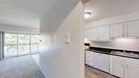 This two-bedroom, two-bathroom unit in Southfield, Michigan, offers a practical and efficiently arranged single-floor layout. The kitchen is a functional highlight, featuring white cabinetry, dark granite-style countertops, wood-look flooring, and white appliances including a range and dishwasher. Adjacent to the kitchen, the dining area is defined by warm wood-look flooring and a decorative pendant light fixture, creating a welcoming space for meals.

The living room provides comfortable square footage and connects to a balcony, allowing natural light and outdoor views of surrounding greenery. Both bedrooms are carpeted and bright, with the second bedroom featuring a large window overlooking mature trees. The generously sized primary bedroom includes access to a walk-in closet with extensive built-in shelving and hanging rods, while the second bedroom also offers a standard closet with organized shelving.

Each bathroom is finished with white tile flooring, a tub-shower combination, white vanity cabinetry, and dark countertops consistent with the kitchen's aesthetic. A connecting hallway ties all rooms together cohesively, and three total closets throughout the unit provide ample storage.