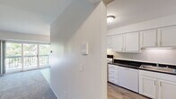 This two-bedroom, two-bathroom unit in Southfield, Michigan, offers a practical and efficiently arranged single-floor layout. The kitchen is a functional highlight, featuring white cabinetry, dark granite-style countertops, wood-look flooring, and white appliances including a range and dishwasher. Adjacent to the kitchen, the dining area is defined by warm wood-look flooring and a decorative pendant light fixture, creating a welcoming space for meals.

The living room provides comfortable square footage and connects to a balcony, allowing natural light and outdoor views of surrounding greenery. Both bedrooms are carpeted and bright, with the second bedroom featuring a large window overlooking mature trees. The generously sized primary bedroom includes access to a walk-in closet with extensive built-in shelving and hanging rods, while the second bedroom also offers a standard closet with organized shelving.

Each bathroom is finished with white tile flooring, a tub-shower combination, white vanity cabinetry, and dark countertops consistent with the kitchen's aesthetic. A connecting hallway ties all rooms together cohesively, and three total closets throughout the unit provide ample storage.