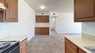 Located on East Fort Lowell Road in Tucson, Arizona, this three-bedroom, two-bathroom single-floor unit offers a practical and well-organized layout. The kitchen is a functional space featuring warm, medium-toned wood cabinetry with ample upper and lower storage, light countertops, a black electric range, a white refrigerator, and a dishwasher. Wood-look flooring runs through the kitchen, while plush carpeting carries through the adjacent dining area and into the rest of the unit. Textured ceilings are present throughout, adding a classic residential character. The three bedrooms are carpeted and bright, with white walls and sufficient space for comfortable furnishing. The primary bedroom includes direct access to a private balcony through a sliding glass door, bringing in natural light and outdoor connectivity. One bedroom features a sliding closet, while another offers a window view of the surrounding neighborhood. The two bathrooms include wood-toned vanity cabinetry with countertop sinks and large mirrors. One bathroom features a tiled soaking tub and wood-look flooring. A dedicated hallway connects the bedrooms and bathrooms, contributing to a clear and efficient circulation path throughout this cozy Tucson residence.