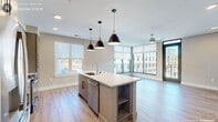 Located at 1250 Hitchings Way in Durham, NC, this contemporary 2-bedroom, 2-bathroom residence offers a thoughtfully designed open-concept layout finished with light hardwood flooring and a neutral color palette throughout. The combined kitchen and living area serves as the heart of the home, anchored by a large center island with a white quartz countertop, undermount sink, and stylish pendant lighting. Taupe cabinetry, stainless steel appliances, and a herringbone tile backsplash complete the modern kitchen aesthetic. The living area is bathed in natural light thanks to expansive floor-to-ceiling windows and a glass door that opens directly onto the private balcony, offering open views of the surrounding area. A ceiling fan adds comfort to the space. The primary bedroom is generously sized, featuring large windows with roller shades and its own dedicated closet with built-in shelving. The en-suite bathroom features a double-sink vanity with quartz countertops, taupe cabinetry, and a walk-in closet. The second bedroom is bright and well-proportioned, also equipped with a ceiling fan and roller-shaded window. The second bathroom offers a soaking tub with white subway tile surround and a single-sink vanity. A hallway with two closets ensures ample storage throughout.