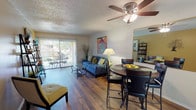 This single-floor residence offers a thoughtfully designed layout that balances comfort and functionality. The open-concept living and dining area serves as the heart of the home, featuring warm hardwood flooring, a ceiling fan with light fixture, and a sliding glass door that floods the space with natural light and provides direct access to a private outdoor patio. The living area is framed by neutral walls accented with a warm yellow tone, creating an inviting atmosphere. The galley-style kitchen is efficiently designed with white cabinetry, granite-look countertops, a stainless steel double sink, and white appliances, including a full-size refrigerator. It connects seamlessly to the dining and living areas. Two well-sized bedrooms each feature plush carpeting, ceiling fans, and closets with built-in storage. The primary bedroom includes a walk-in closet, while the secondary bedroom offers a standard sliding-door closet. A full bathroom with a shower/tub combination and hardwood flooring serves the common areas. A dedicated in-unit laundry space accommodates a full-size washer and dryer with additional wire shelving for storage. Throughout the home, textured ceilings and consistent finishes contribute to a cohesive and comfortable living environment.