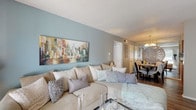 This single-story, one-bedroom, one-bathroom residence offers a thoughtfully designed open-concept layout that connects the living, dining, and kitchen areas into a cohesive and functional living space. The living room serves as the heart of the home, featuring rich wood-look flooring, a calming blue-gray accent wall, and sliding glass doors that invite natural light while providing access to an outdoor area. The spacious sectional seating area flows naturally into the dining space, which is highlighted by a chandelier overhead and an open sightline to the kitchen.

The kitchen is outfitted with warm wood cabinetry, a mosaic tile backsplash, granite-tone countertops, and black appliances, including a refrigerator and electric range. The galley-style layout maximizes efficiency while maintaining an organized, functional workspace.

The bedroom is generously sized, featuring a ceiling fan with light, wood-look flooring, and windows with natural light. A walk-in closet provides ample storage. The full bathroom includes a vanity with granite-tone countertops, a tub-shower combination, wood cabinetry with overhead storage, and consistent wood-look flooring throughout. The overall ambiance of the residence is warm, cohesive, and move-in ready.