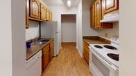 Located at 261 Colonnade Dr in Charlottesville, Virginia, this single-floor unit offers a practical and well-organized layout throughout. The living and dining area features wood-look flooring and receives natural light through a sliding glass door that opens to the outdoors, creating a bright and welcoming atmosphere. A hallway connects the main living space to the private areas of the unit.

The galley-style kitchen is efficiently designed with warm honey-toned cabinetry, dark granite-style countertops, and wood-look flooring. It is equipped with white appliances including a refrigerator, electric range, and dishwasher, along with ample upper and lower cabinet storage. Track lighting overhead keeps the space well-lit.

The bedrooms are carpeted and offer generous wall space, with at least one room featuring a windowed view of surrounding greenery and another equipped with a built-in closet with bifold doors. The bathrooms include a vanity bathroom with an extended countertop, a large mirror, and overhead lighting, as well as a second bathroom featuring a glass-enclosed shower stall. Both bathrooms have wood-look flooring and clean, neutral finishes throughout.
