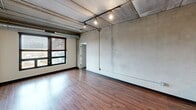 This 870 square foot apartment, located at 618 S Main St in Ann Arbor, MI, showcases a striking blend of industrial and modern design elements. The space is characterized by its open floor plan and exposed concrete ceilings, which create a loft-like atmosphere throughout. The apartment features two bedrooms, with the primary bedroom offering a generous 170 square feet of space.

The kitchen is a standout feature, boasting sleek stainless steel appliances, honey-colored wood cabinetry, and a built-in wine rack. A large island with a dark countertop provides ample workspace and serves as a natural divider between the kitchen and living areas. The bathroom continues the modern aesthetic with a dark vanity and wooden flooring.

Throughout the apartment, the interplay of materials is evident. Warm wood flooring in the main living areas and kitchen contrasts beautifully with the industrial concrete ceilings and exposed ductwork. Large windows allow natural light to flood the space, while track lighting adds a contemporary touch.

The bedrooms feature plush carpeting for comfort, with one room showcasing floor-to-ceiling windows that offer expansive views. A dedicated closet space ensures adequate storage. The overall design aesthetic seamlessly blends functionality with style, creating a unique urban living experience in the heart of Ann Arbor.