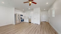 Located at 4288 W Denali Ln in Phoenix, AZ, this two-story home offers a well-designed layout spread across two floors. The ground level houses an attached garage with an automatic opener, providing convenient and secure parking. The main living floor features an open-concept kitchen and living room with light wood-look flooring and ceiling fans throughout. The kitchen is outfitted with white shaker cabinets, quartz countertops, a subway tile backsplash, a stainless steel undermount sink, and a full suite of stainless steel appliances including a refrigerator, range, microwave, and dishwasher. The bright living area extends to a sliding glass door that opens to an outdoor space with views of mature palm trees, filling the room with natural light. Upstairs, the generously sized primary bedroom includes a walk-in closet with built-in shelving and rods, as well as a private en-suite bathroom with a glass-enclosed walk-in shower and elegant tile surround. A second bedroom, additional bathrooms, and a dedicated laundry room with a full-size washer and dryer complete the upper level. Clean white walls and light flooring throughout give the home a bright, modern ambiance.