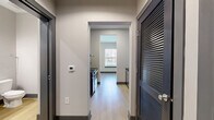 Located at 1220 Second Ave N in Nashville, TN, this efficiently designed one-bedroom, one-bathroom unit offers a thoughtful layout across a single floor. Light wood flooring flows throughout, complementing the clean, neutral palette that defines the space's modern aesthetic.

The living area is accessed through a striking sliding barn-style door and features smooth walls, recessed lighting, and a spacious, open feel. The bedroom is generously proportioned, offering two windows that invite natural light and provide views of the surrounding neighborhood.

The kitchen is appointed with rich walnut-toned cabinetry, dark granite countertops, and a textured tile backsplash that adds visual depth. Stainless steel appliances, including a dishwasher and refrigerator, complete the functional and stylish cooking space.

The bathroom presents a contemporary design with a floating vanity featuring open wood shelving, a white countertop, and a large mirror with overhead lighting. A glass-enclosed, tiled walk-in shower adds a refined touch. The unit also includes a hallway and a closet, maximizing storage and flow within the compact footprint. Overall, the space delivers a clean, urban living experience with modern finishes throughout.