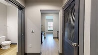 Located at 1220 Second Ave N in Nashville, TN, this efficiently designed one-bedroom, one-bathroom unit offers a thoughtful layout across a single floor. Light wood flooring flows throughout, complementing the clean, neutral palette that defines the space's modern aesthetic.

The living area is accessed through a striking sliding barn-style door and features smooth walls, recessed lighting, and a spacious, open feel. The bedroom is generously proportioned, offering two windows that invite natural light and provide views of the surrounding neighborhood.

The kitchen is appointed with rich walnut-toned cabinetry, dark granite countertops, and a textured tile backsplash that adds visual depth. Stainless steel appliances, including a dishwasher and refrigerator, complete the functional and stylish cooking space.

The bathroom presents a contemporary design with a floating vanity featuring open wood shelving, a white countertop, and a large mirror with overhead lighting. A glass-enclosed, tiled walk-in shower adds a refined touch. The unit also includes a hallway and a closet, maximizing storage and flow within the compact footprint. Overall, the space delivers a clean, urban living experience with modern finishes throughout.