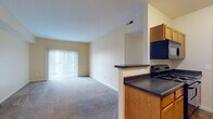 Located at 785 Cross Pointe Rd in Gahanna, Ohio, this single-floor residence offers a well-organized and functional layout designed for comfortable everyday living. The open-concept living and dining area is finished with plush carpeting and is bathed in natural light through a large sliding glass door fitted with vertical blinds, creating a bright and welcoming atmosphere. A half-wall peninsula connects the living space to the kitchen, which features warm oak cabinetry, dark countertops, and a full suite of black appliances including a range, dishwasher, refrigerator, and over-range microwave. The kitchen is finished with a distinctive diamond-patterned tile floor, providing a clean contrast to the carpeted living areas. A pendant light adds a decorative touch to the transition between spaces. The bedrooms are generously sized, carpeted, and filled with natural light from windows overlooking the exterior. Notably, one bedroom offers the convenience of dual closets with wire shelving systems, providing abundant storage. The bathrooms are well-appointed with oak vanities, dark countertops, tile flooring matching the kitchen, and a full-sized soaking tub with a shower. Throughout the residence, neutral warm tones and clean finishes create a cohesive and inviting ambiance.