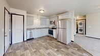 Located in the Countryside neighborhood of Rapid City, South Dakota, this single-floor unit offers a practical and well-finished layout across several distinct living spaces. The floor plan, visible in the 3D model, reveals a thoughtfully arranged interior with clear separation between the kitchen, living areas, bedrooms, and bathroom.

The kitchen is a standout feature, equipped with a full suite of stainless steel appliances including a refrigerator, electric range, built-in microwave, and dishwasher. White shaker-style cabinetry with granite-look countertops lines the walls in an L-shaped configuration, complemented by wood-look vinyl plank flooring and pendant lighting overhead. The space is both functional and visually cohesive.

The living area is bright and open, featuring plush carpeting, a ceiling fan, and a large window that allows natural light and views of the surrounding neighborhood and distant hills. The bedrooms share a similar aesthetic—neutral walls, carpet flooring, and windows overlooking the outdoors.

The bathroom features wood-look tile flooring, white cabinetry with matching granite-look countertops, a large mirror, and ample storage, maintaining the consistent design language found throughout the unit.
