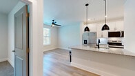 Located at 34 Ramsey Branch Rd in Freeport, Florida, this efficiently designed single-story home offers one bedroom and three bathrooms within a thoughtfully arranged floor plan. The interior is finished with light-toned hardwood-style flooring that runs through the main living areas, creating a clean and cohesive aesthetic throughout.

The open-concept kitchen and living area serves as the heart of the home. The kitchen is outfitted with white shaker cabinetry, granite countertops, a central island with a built-in sink, stainless steel appliances including a French door refrigerator, and stylish matte black pendant lighting. Recessed ceiling lights provide additional illumination, while a ceiling fan in the living area promotes airflow. A large window invites natural light and offers views of surrounding greenery.

The hallway connects the main living space to the bedroom, closets, and bathrooms, with louvered and paneled gray doors adding architectural character. The bedroom features soft carpeting, a spacious closet, and a window with natural light. At least one bathroom includes a glass-enclosed walk-in shower with floor-to-ceiling white tile and brushed nickel fixtures. A dedicated laundry room and two closets round out the functional offerings of this well-appointed home.