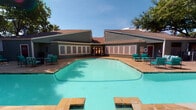 Located in Arlington, Texas, this single-floor residence at 1237 Enclave Cir offers a thoughtfully designed living space with standout architectural details throughout. The living room serves as the heart of the home, showcasing soaring vaulted ceilings that lend an airy, open feel to the space. A classic brick fireplace anchors one wall, adding warmth and character, while French doors flood the room with natural light and provide direct access to the outdoors. The living area flows seamlessly into a dining space and a well-appointed kitchen, featuring dark cabinetry and a breakfast bar with stone countertops — ideal for both casual meals and entertaining. Neutral-toned carpeting and wood-style flooring run throughout, complementing the soft gray wall palette. The layout is functional and connected, with defined zones for living, dining, and cooking that feel cohesive yet distinct. Beyond the interior, residents enjoy access to a generously sized community swimming pool, surrounded by a spacious sundeck and comfortable seating, all framed by mature trees and the building's attractive pitched-roof architecture. This property combines comfortable interior living with inviting outdoor amenities in a well-established Arlington community.
