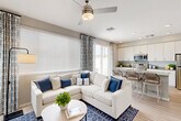 Located in Litchfield Park, AZ, this well-designed one-bedroom, one-bathroom residence offers a thoughtful open-concept layout that maximizes every square foot. Light wood-style flooring flows throughout, complementing the neutral warm-gray palette that gives the space a clean, contemporary feel.

The combined living room and kitchen area serves as the heart of the home. Large windows fitted with horizontal blinds and patterned drape panels invite abundant natural light, while a ceiling fan adds comfort. The kitchen is outfitted with crisp white cabinetry extending to the ceiling, stone-look countertops, stainless steel appliances including a range, over-the-range microwave, and refrigerator, and a spacious island with an undermount sink and seating for casual dining.

A hallway connects the living area to the private bedroom and bathroom. The bedroom comfortably accommodates a full-size bed and features a window with blinds and patterned curtains, providing natural light while maintaining privacy. The full bathroom presents white cabinetry, a stone-look countertop vanity with an undermount sink, and a high window for ventilation and light.

The exterior includes a private patio with paver tiles, a patch of turf, and a fully enclosed vinyl privacy fence, offering a quiet outdoor retreat in the Arizona sunshine.