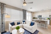 Located in Litchfield Park, AZ, this well-designed one-bedroom, one-bathroom residence offers a thoughtful open-concept layout that maximizes every square foot. Light wood-style flooring flows throughout, complementing the neutral warm-gray palette that gives the space a clean, contemporary feel.

The combined living room and kitchen area serves as the heart of the home. Large windows fitted with horizontal blinds and patterned drape panels invite abundant natural light, while a ceiling fan adds comfort. The kitchen is outfitted with crisp white cabinetry extending to the ceiling, stone-look countertops, stainless steel appliances including a range, over-the-range microwave, and refrigerator, and a spacious island with an undermount sink and seating for casual dining.

A hallway connects the living area to the private bedroom and bathroom. The bedroom comfortably accommodates a full-size bed and features a window with blinds and patterned curtains, providing natural light while maintaining privacy. The full bathroom presents white cabinetry, a stone-look countertop vanity with an undermount sink, and a high window for ventilation and light.

The exterior includes a private patio with paver tiles, a patch of turf, and a fully enclosed vinyl privacy fence, offering a quiet outdoor retreat in the Arizona sunshine.