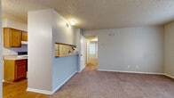Located at 1401 Schertz Pkwy in Schertz, TX, this single-floor, 2-bedroom, 1-bathroom residence offers a practical and comfortable layout. The carpeted living room serves as the heart of the home, accessible directly from the front entry and connected to the kitchen via a convenient pass-through bar that promotes an open feel between the two spaces. The galley-style kitchen is well-equipped with warm wood cabinetry, ample counter space, a coil-burner electric range, a full-size refrigerator, and a sink — all set atop easy-care hardwood-style flooring. Both bedrooms are carpeted and feature ceiling fans with light fixtures, textured ceilings, and neutral wall tones. The primary bedroom offers generous proportions along with its own dedicated closet featuring built-in shelving, while the second bedroom benefits from natural light through a window with blinds and its own closet access. A hallway connects the bedrooms to the shared full bathroom, which includes a tub/shower combination with tiled surround, a toilet, vanity with wood cabinetry above, and hardwood-style flooring. Throughout the residence, the consistent use of neutral tones, textured ceilings, and carpet creates a cohesive and move-in-ready atmosphere.
