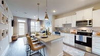 This one-bedroom, one-bathroom residence at Annabelle on Main in Duluth, GA offers a well-designed, single-floor layout that maximizes both function and style. The open-concept living area flows seamlessly from the kitchen, creating a bright, connected space ideal for everyday living and entertaining. The kitchen is outfitted with crisp white shaker-style cabinetry, granite countertops, a subway tile backsplash, and a full suite of stainless steel appliances including a range, microwave, dishwasher, and refrigerator. A central island with granite counters and pendant lighting serves as a natural gathering point, with bar seating providing an informal dining option. Wood-style flooring runs throughout the main living areas, adding warmth and continuity. The living room features large windows with views to the outdoors, allowing natural light to fill the space. The bedroom is carpeted for comfort, with generous window coverage, a ceiling fan, and room for ample furnishings. The bathroom is spacious and well-appointed, featuring a wide granite-topped vanity with white cabinetry, a large mirror, and a walk-in shower. The overall aesthetic is modern and neutral, with clean finishes throughout that provide a polished, move-in-ready feel.