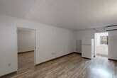 Located at 2032 NE Evangeline Trwy in Lafayette, Louisiana, this single-floor unit offers a practical and efficiently designed layout across two living areas, three bathrooms, and a kitchen. The living areas feature wood-look laminate flooring and white-painted walls accented by dark baseboards, creating a clean, neutral aesthetic. Textured popcorn ceilings are consistent throughout the space. One living area includes a dark entry door with an adjacent window fitted with horizontal blinds, allowing natural light to filter in. The kitchen is equipped with white cabinetry, light-toned countertops, a built-in electric cooktop, an over-the-range GE microwave, and a full-size refrigerator. A hallway area features additional white cabinetry with countertop space and drop-panel ceiling tiles. The three bathrooms are functionally appointed, each featuring a tub-shower combination with chrome grab bars for accessibility support, tile flooring, and standard fixtures. The overall design of the space is straightforward and utilitarian, with a consistent white-and-neutral color palette maintained throughout. The layout flows efficiently between rooms, making practical use of the available footprint.