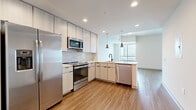 Located in the heart of Charlotte, NC, this modern single-floor residence on W Martin Luther King Jr Blvd offers a thoughtfully designed open-concept layout with clean lines and contemporary finishes throughout. Wood-look flooring runs seamlessly across the main living areas, complementing the bright, neutral color palette that gives the space an airy, welcoming feel.

The kitchen is a standout feature, equipped with a full suite of stainless steel appliances including a French door refrigerator, electric range, built-in microwave, and dishwasher. Light wood cabinetry extends to the ceiling, providing generous storage, while a white subway tile backsplash and pendant lighting over the sink add stylish detail. The kitchen opens directly to the living area, making it ideal for entertaining.

The living room benefits from large windows that draw in abundant natural light, with a door leading to a private balcony offering views of the surrounding cityscape. The bedroom is generously proportioned, featuring a ceiling fan, access to a full bathroom, and additional closet space.

The bathroom is finished with large-format tile flooring, a sleek floating vanity with a white countertop, a soaking tub, and a separate walk-in shower. The entryway includes a louvered closet door for convenient storage. This residence combines modern urban living with practical, well-appointed interiors in a prime Charlotte location.