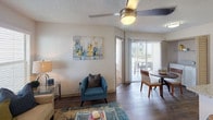 This single-story residence offers a thoughtfully designed layout that balances comfort and functionality across its living spaces. The open-concept living and dining area serves as the heart of the home, featuring wood-style flooring, a ceiling fan with integrated lighting, and a sliding glass door that leads to a private patio, allowing natural light to fill the space and providing outdoor views. A large window in the living area further brightens the room and overlooks the surrounding greenery.

The kitchen is equipped with white shaker-style cabinetry, granite countertops, a tile backsplash, and stainless steel appliances, including a range, microwave, and refrigerator. The clean, modern finishes create a cohesive and functional cooking environment.

The primary bedroom features plush carpeting, a window for natural light, and direct access to an en-suite bathroom via a sliding barn door. The en-suite includes a granite-topped vanity with white cabinetry. A second bedroom, also carpeted and well-lit, is served by a full bathroom featuring a granite vanity, white cabinetry, and a tub-shower combination. Both bathrooms maintain consistent, updated finishes throughout. Textured walls are present across the residence, adding a subtle design detail to the overall aesthetic.