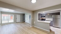 This two-story home offers a clean, modern aesthetic throughout, with thoughtful design details across both levels. The main floor features an open-concept living and dining area finished with light wood-style flooring and neutral gray walls, creating a bright and welcoming atmosphere. Large windows fitted with blinds allow natural light to fill the space while providing privacy. A staircase and closet storage are conveniently located near the entryway.

The kitchen is a standout feature, equipped with gray shaker-style cabinetry, quartz countertops, a classic white subway tile backsplash, and a full suite of stainless steel appliances including a refrigerator, range, and over-the-range microwave. A pass-through counter connects the kitchen to the main living area, enhancing the open flow. Track lighting overhead provides ample task illumination.

Upstairs, the bedrooms are carpeted for comfort and include windows that bring in natural light. The primary bedroom is generously sized with access to additional rooms or closets. The bathroom is well-finished with a gray vanity, quartz countertop, and a tub-shower combination surrounded by large-format tile. The overall design is contemporary and move-in ready, with consistent finishes throughout both floors.